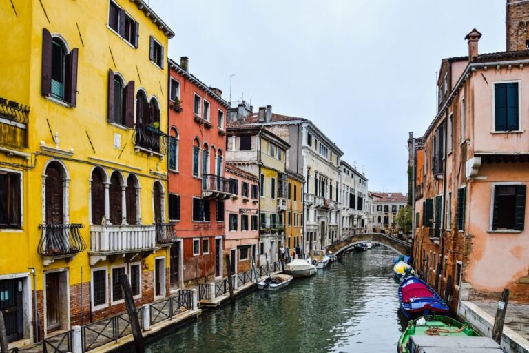 Vibrant buildings line a tranquil canal in Venice, showcasing classic architecture and picturesque gondolas.