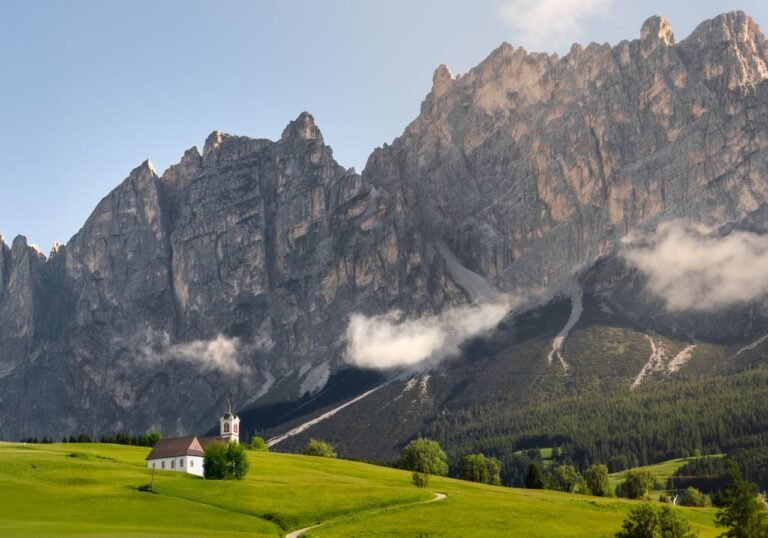 Church in a green meadow beneath the Dolomites mountains