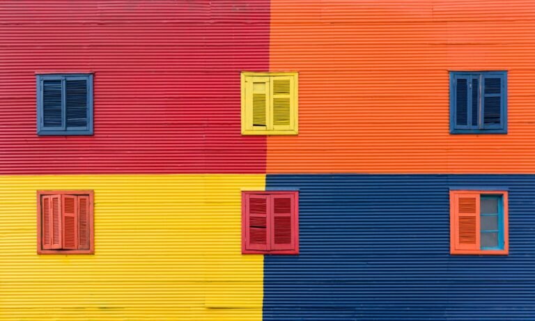 Brightly colored building facade with blue, red, yellow, and orange shutters.
