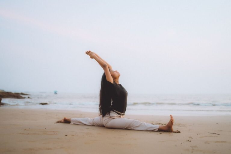 Serene beach yoga session at sunrise with woman performing splits, embodying calm and balance.