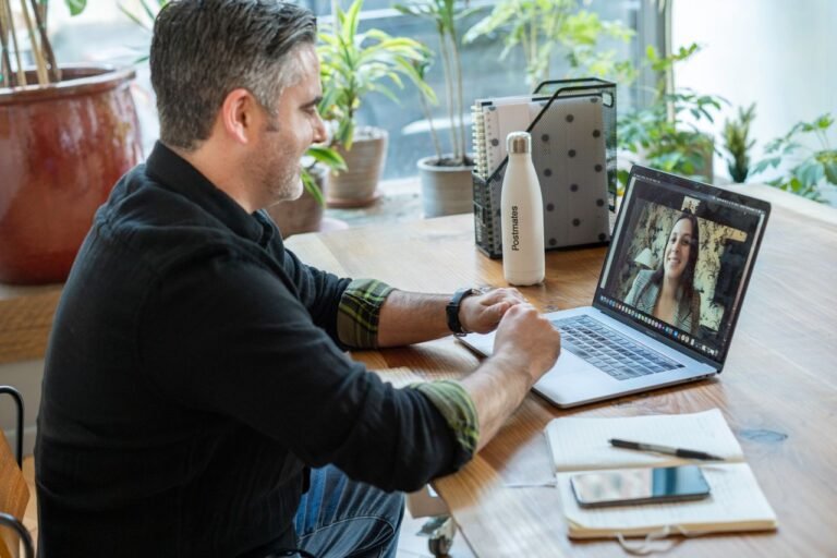 A man participates in a virtual meeting from his home workspace, focusing on remote work.